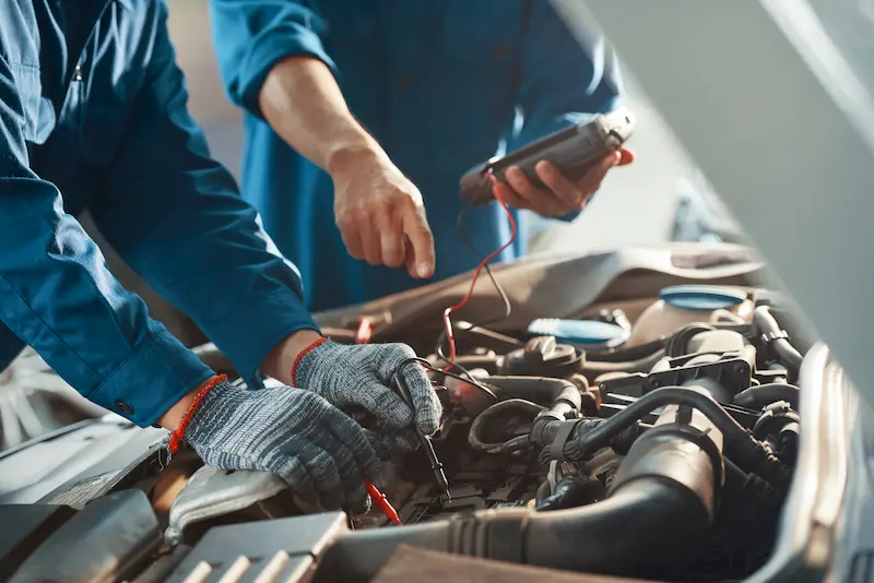 Mecánicos revisan batería del coche de segunda mano antes de comprarlo