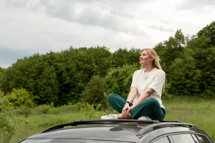 Mujer encima de su coche de ocasión en el campo