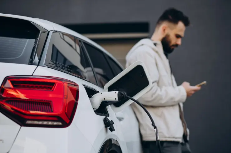 Hombre apoyado en un coche eléctrico