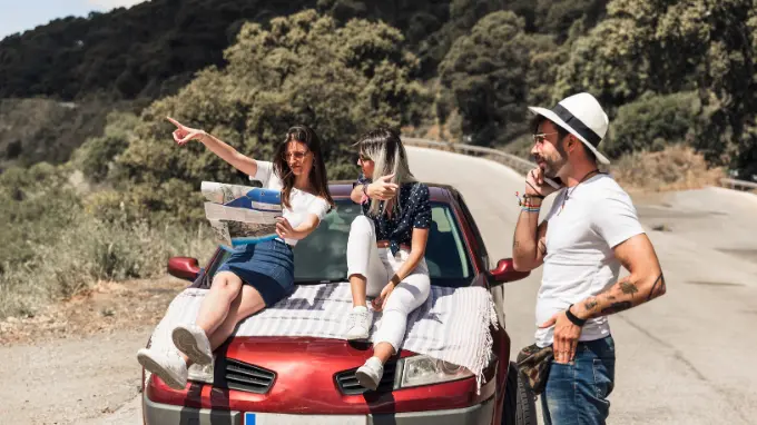 amigos amigos encima de un coche con un plano planificando su ruta