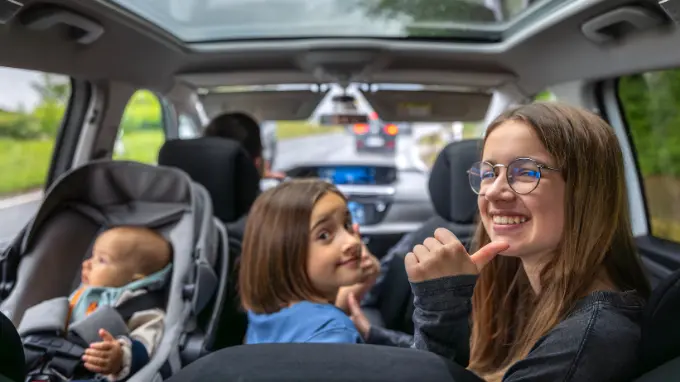 tres niñas con su familia de viaje en un coche de ocasión