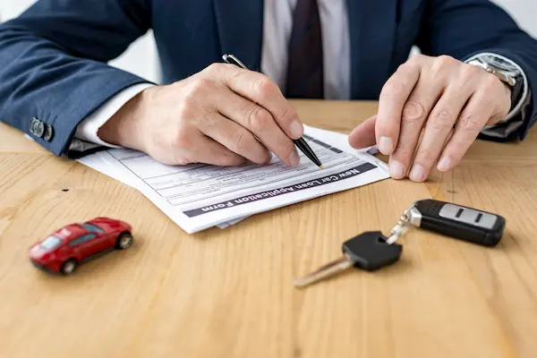 Cliente firma los papeles para la compra de un coche usado